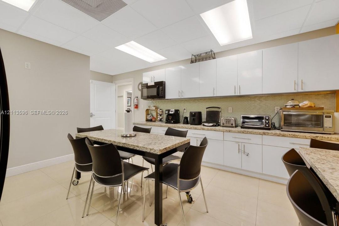 Kitchen featuring white high-gloss cabinetry, stone-finish countertops, tiled backsplash, recessed lighting, and tile flooring