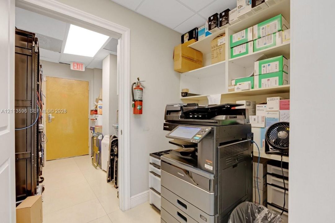Utility room featuring white tile flooring, recessed ceiling lighting, and integrated wall-mounted storage shelving