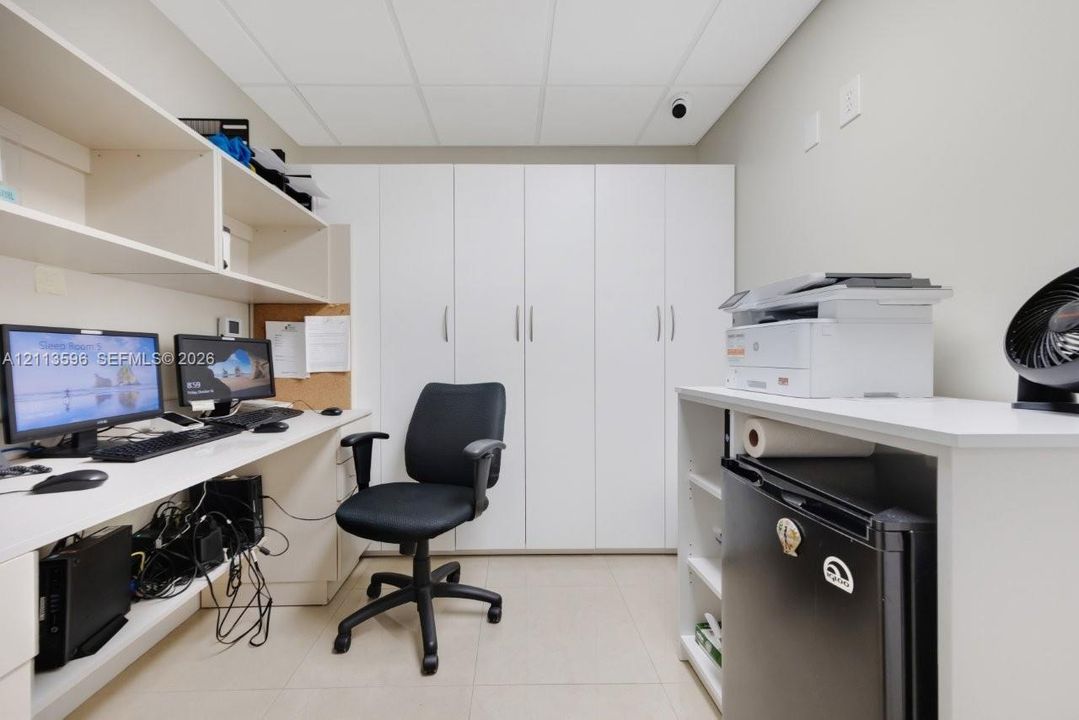 Built-in floor-to-ceiling cabinetry, integrated desk surface with overhead shelving, and neutral tile flooring