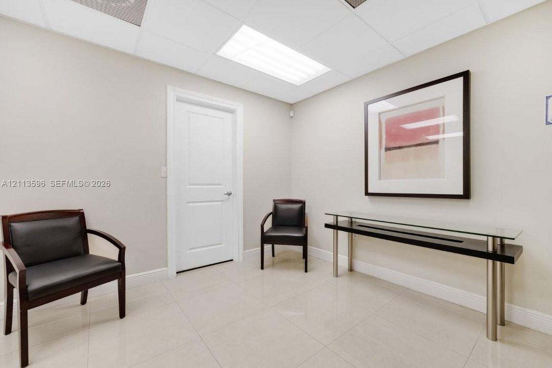 Neutral wall color, polished tile flooring, drop ceiling with recessed lighting, and a solid-core interior door