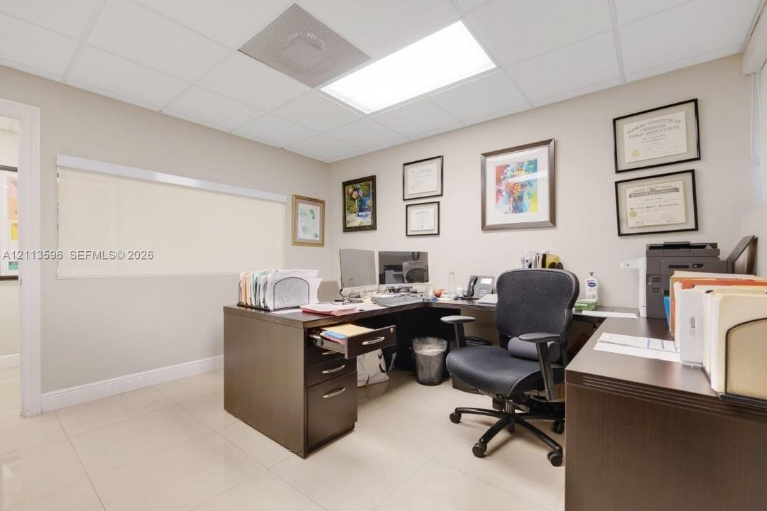 Interior space featuring large-format tile flooring, a suspended grid ceiling, and recessed panel lighting