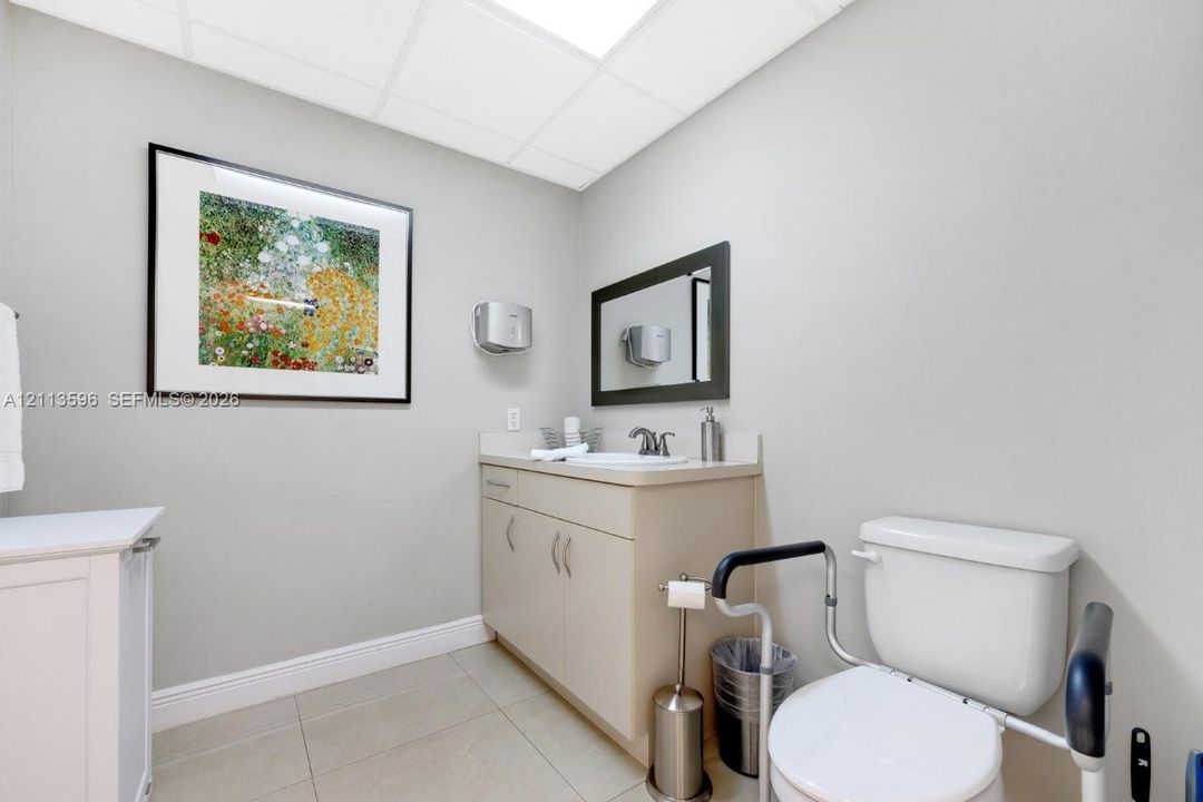 Restroom featuring a vanity with integrated sink, drop ceiling, tile flooring, and wall-mounted mirror
