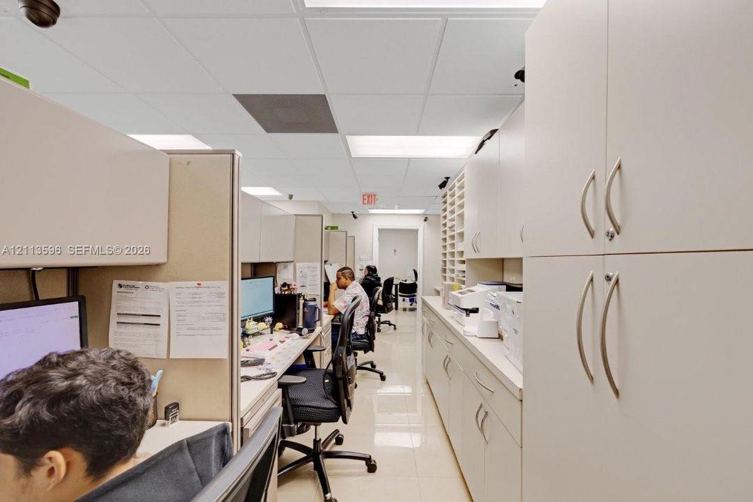 Office space featuring built-in floor-to-ceiling cabinetry, integrated storage shelving, drop ceiling lighting, and polished tile flooring