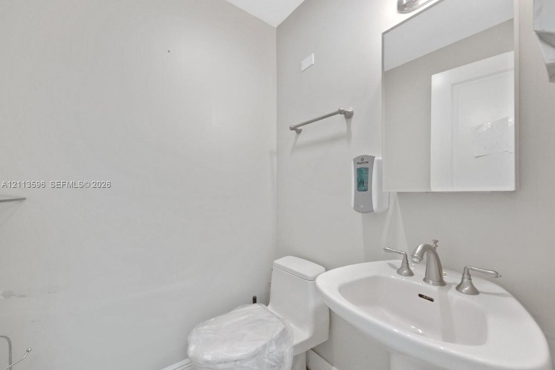 Pedestal sink with a widespread brushed-nickel faucet, rectangular mirror, and high-profile toilet