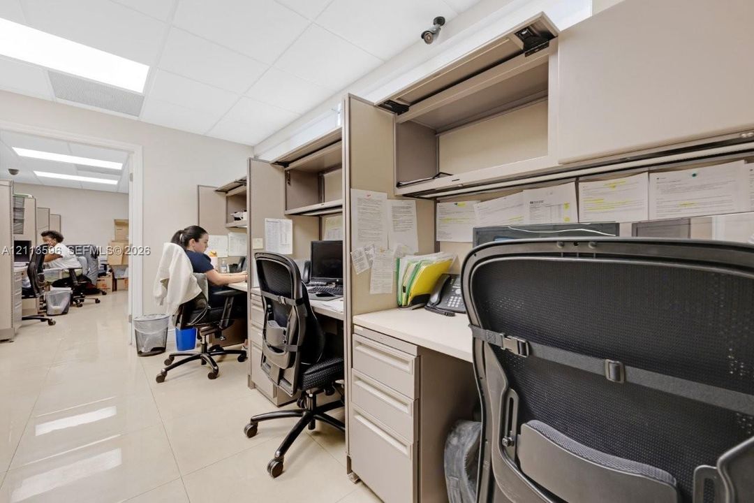 Work area featuring modular workstation partitions, built-in overhead storage cabinetry, solid-surface desktops, multi-drawer storage pedestals, and recessed lighting