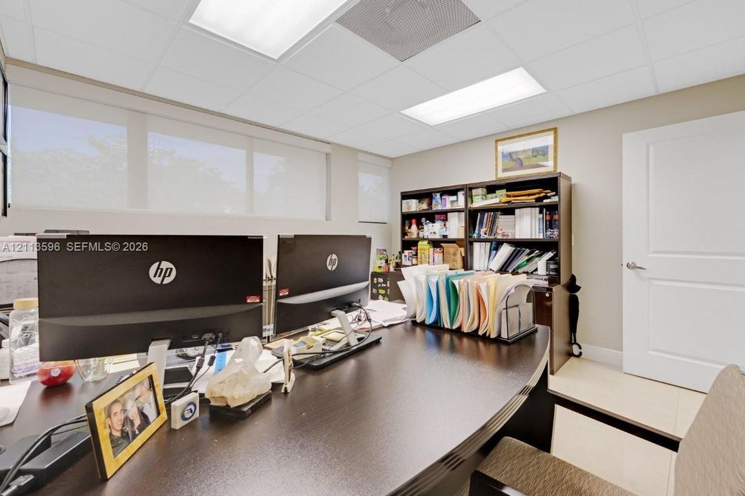 Room featuring neutral wall paint, large windows with retractable shades, tile flooring, and a drop ceiling with recessed panel lighting