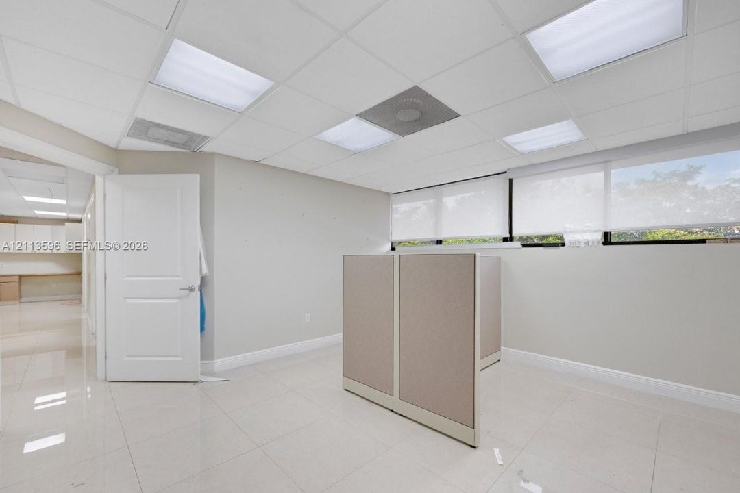 Tiled flooring, recessed drop ceiling lighting, and large windows with roller shades