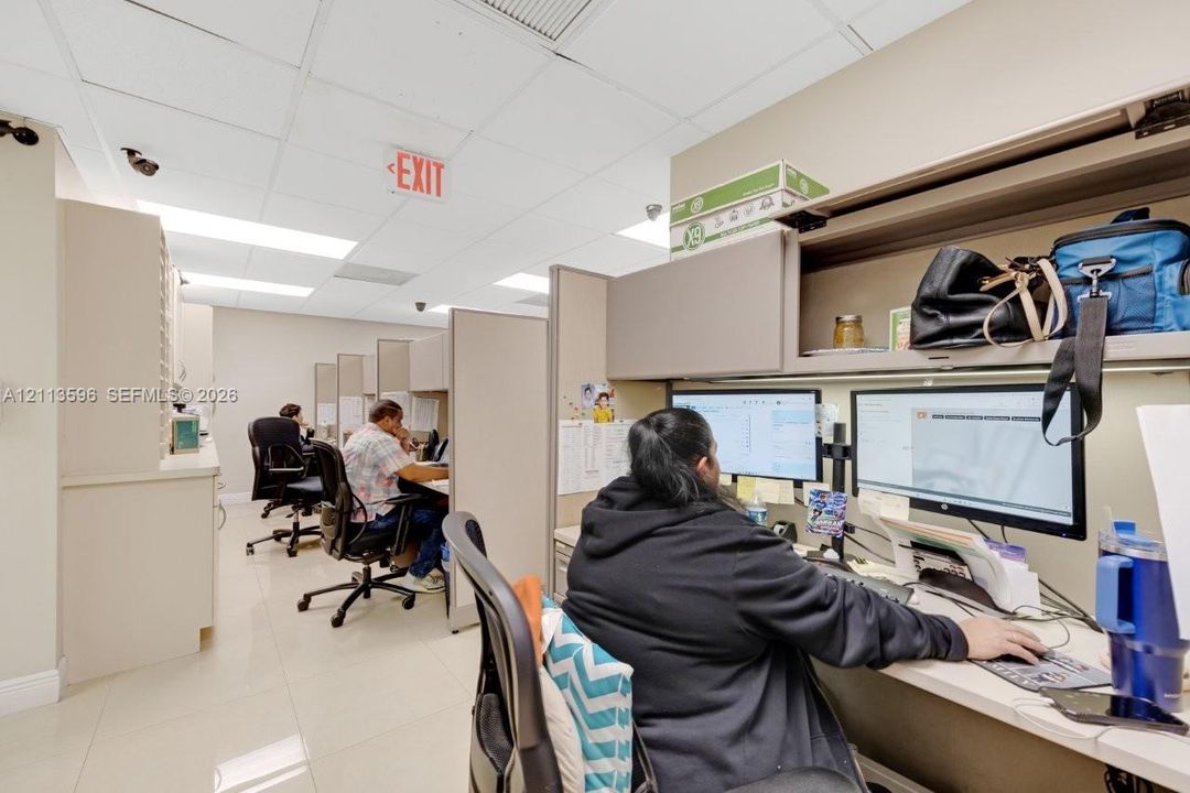 Work area featuring built-in cabinetry, overhead storage units, laminate surfaces, and tiled flooring