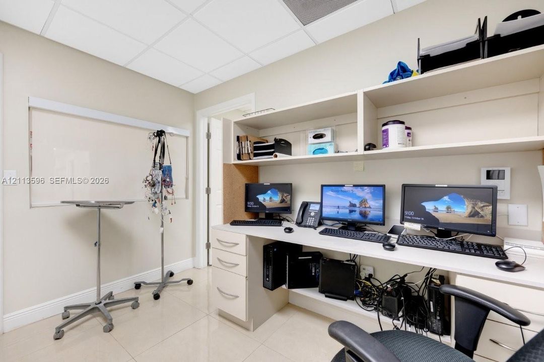 Built-in white cabinetry with integrated workspace, durable tile flooring, and drop ceiling