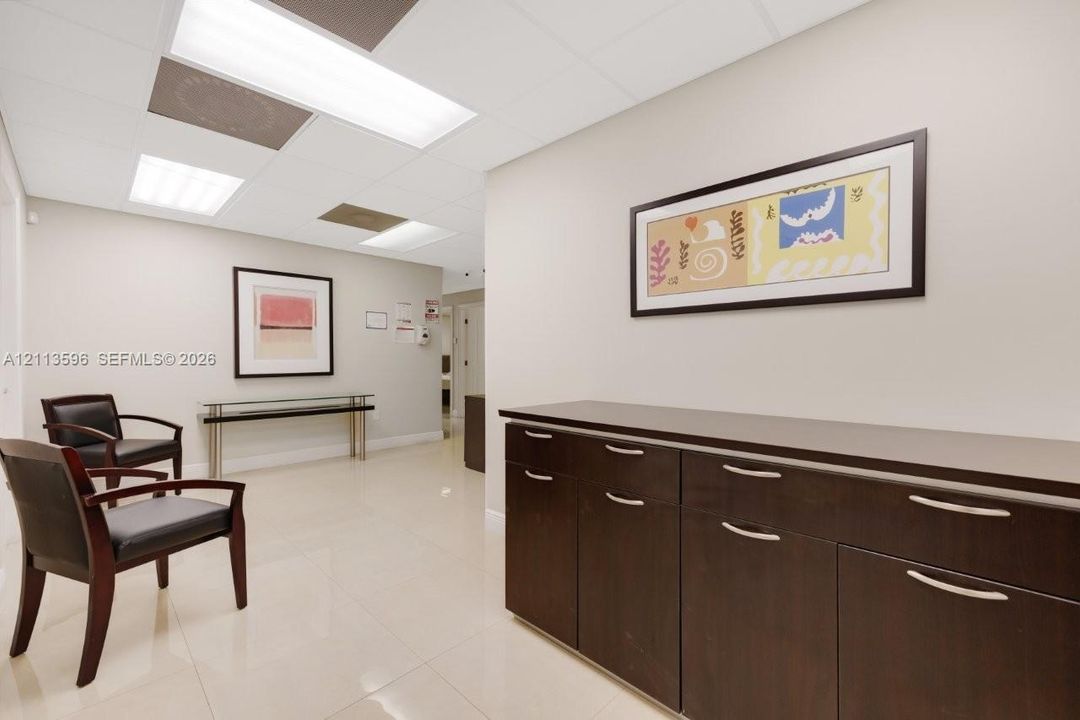 Interior space featuring large-format tile flooring, drop-ceiling grid panels with recessed lighting, and built-in dark wood cabinetry with silver-tone pulls