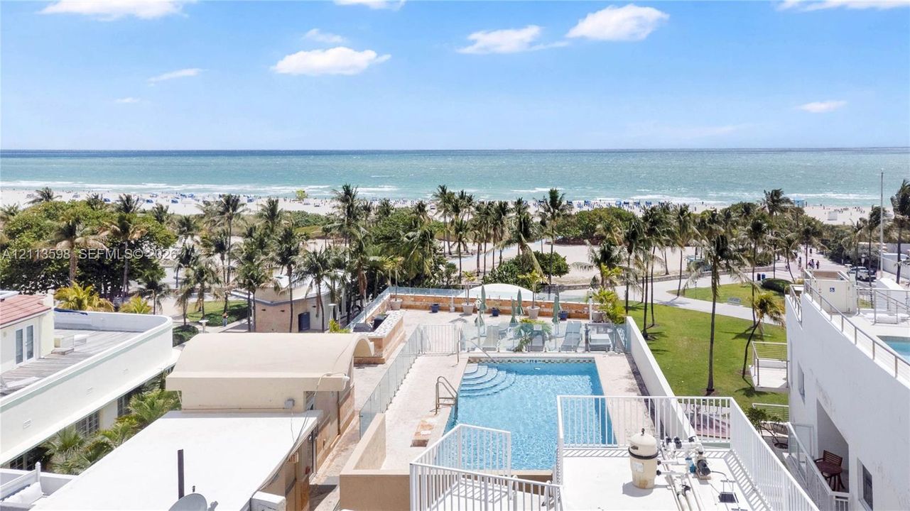 Rooftop terrace featuring an in-ground swimming pool, glass paneled railings, and expansive coastal scenery