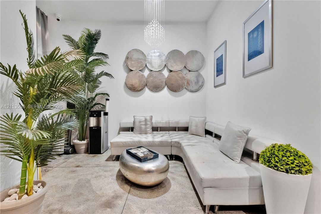Polished concrete flooring, contemporary crystal chandelier, and neutral wall surfaces