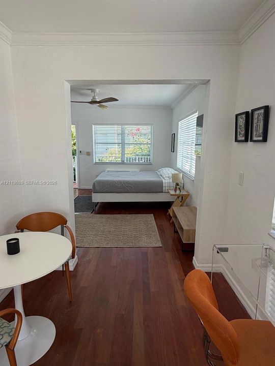 Wood-finish flooring, crown molding, and ceiling-mounted fan, featuring multiple windows with horizontal blinds