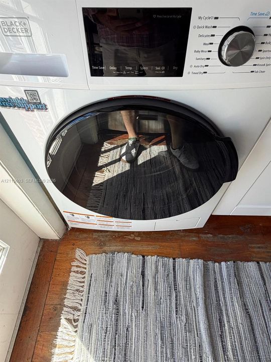 White front-load washing machine featuring a black-rimmed circular glass door, digital control interface with multiple cycle options, and metal dial selector