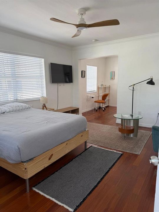 Wood-finish flooring, white walls, and a ceiling fan with integrated lighting