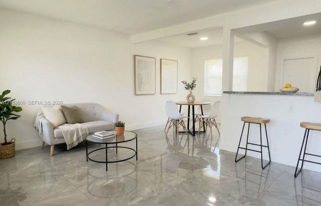 Large-format tile flooring, recessed lighting, and a breakfast bar with a stone-finish countertop