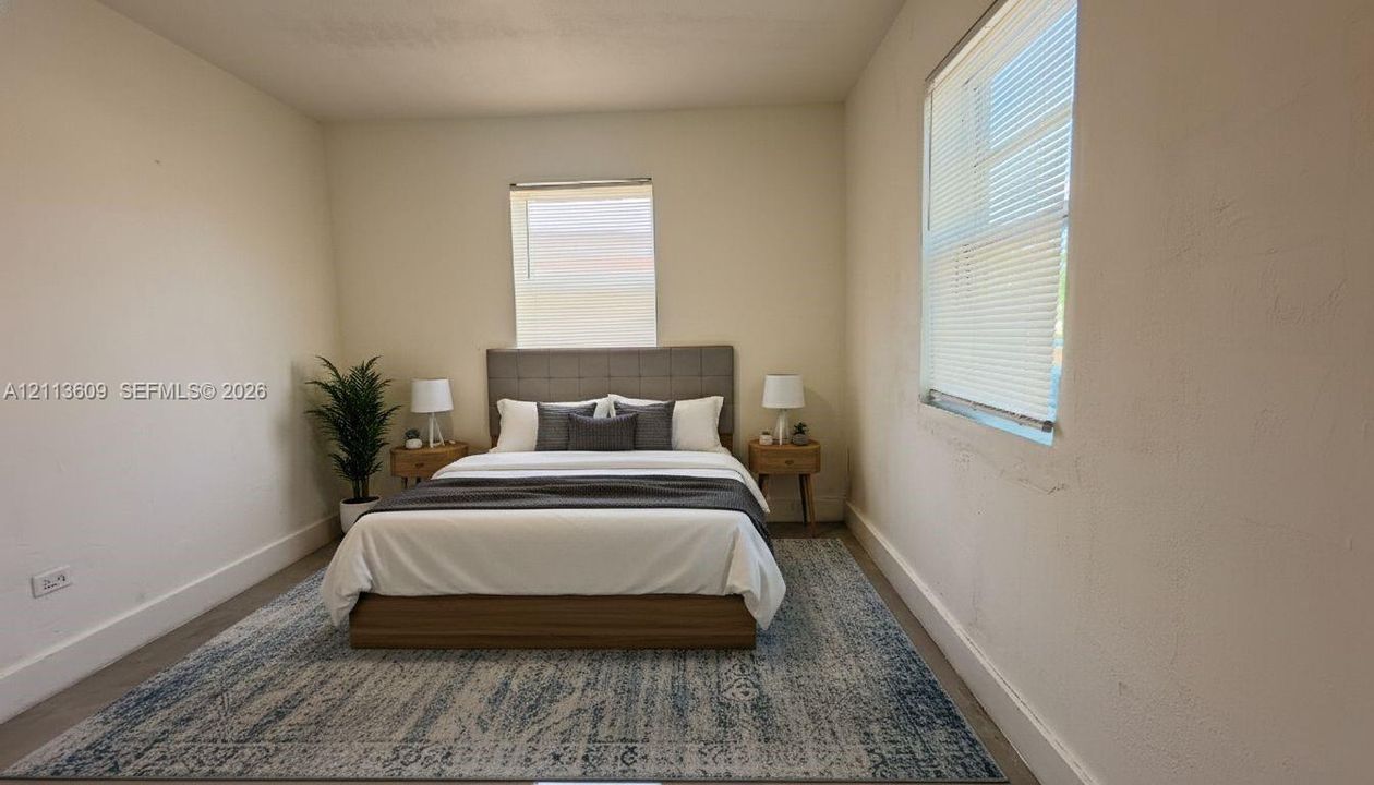 Neutral-toned room featuring a window with integrated blinds, wood-finish flooring, and textured wall surfaces