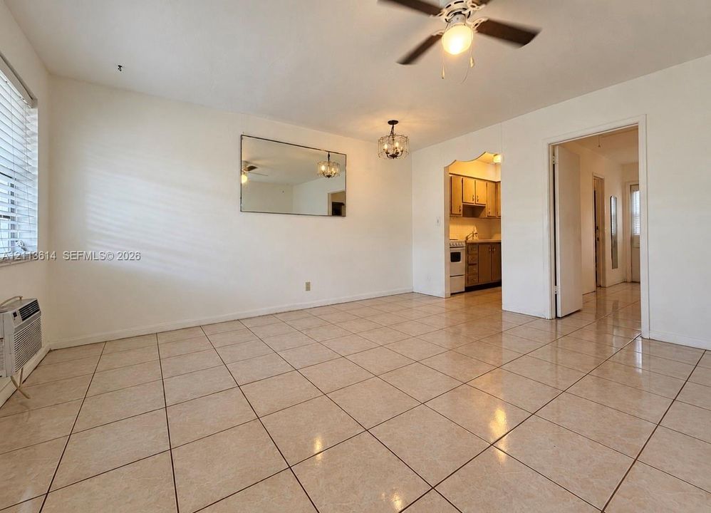 Ceramic tile flooring, neutral wall finishes, integrated wall-mounted mirror, ceiling fan with light fixture, and arched entryway