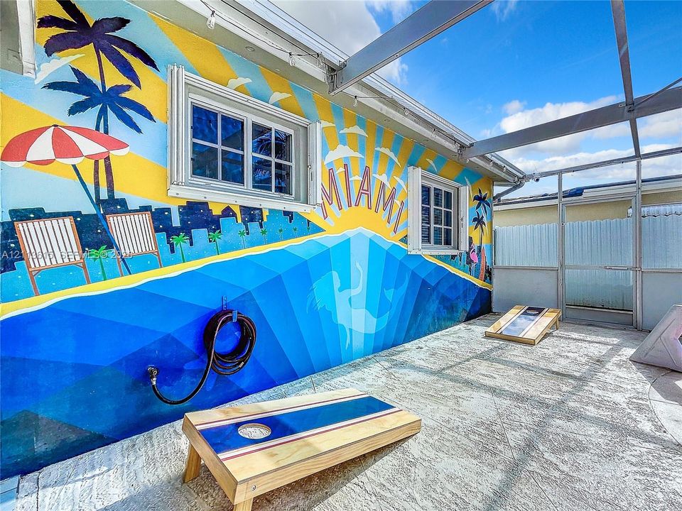 Screened-in patio featuring concrete flooring, aluminum framing, and a decorative exterior mural