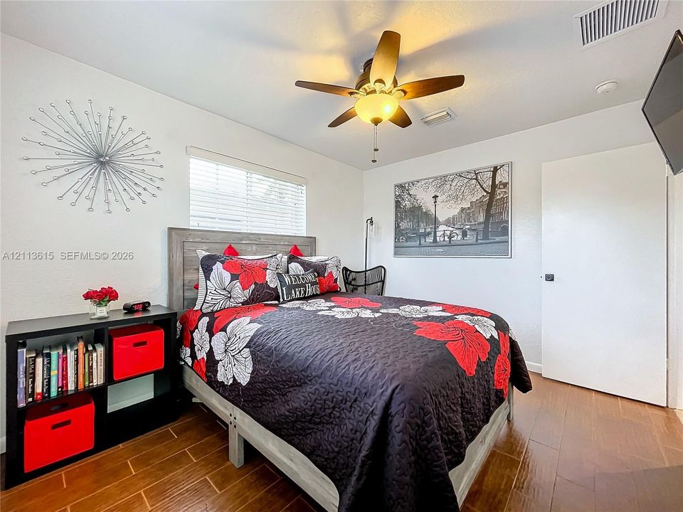 Wood-finish tile flooring, ceiling fan with integrated lighting, and horizontal window blinds