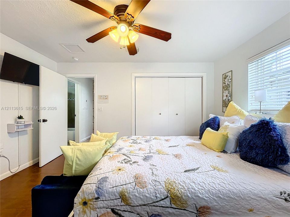 Room featuring wood-finish flooring, ceiling fan with integrated lighting, closet with double doors, and horizontal window blinds
