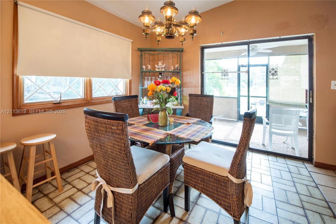 Dining area featuring ceramic tile flooring, multi-pane windows, a multi-arm chandelier, and glass sliding doors leading to an enclosed patio