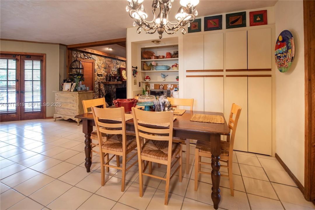 Ceramic tile flooring, floor-to-ceiling built-in cabinetry, recessed open shelving, ornamental chandelier, and double French doors with glass panes