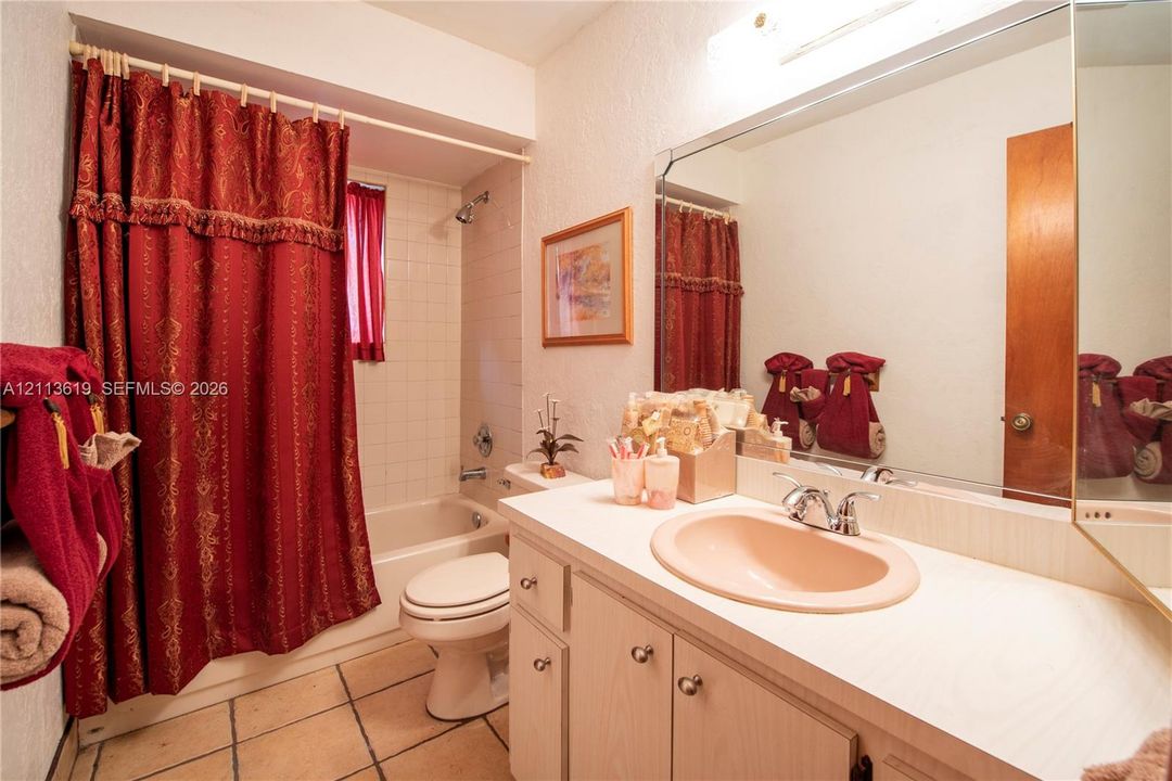 Bathroom featuring a vanity with integrated sink, expansive wall-mounted mirror, light-finish cabinetry, tile flooring, and a shower-tub combination with ceramic wall tile