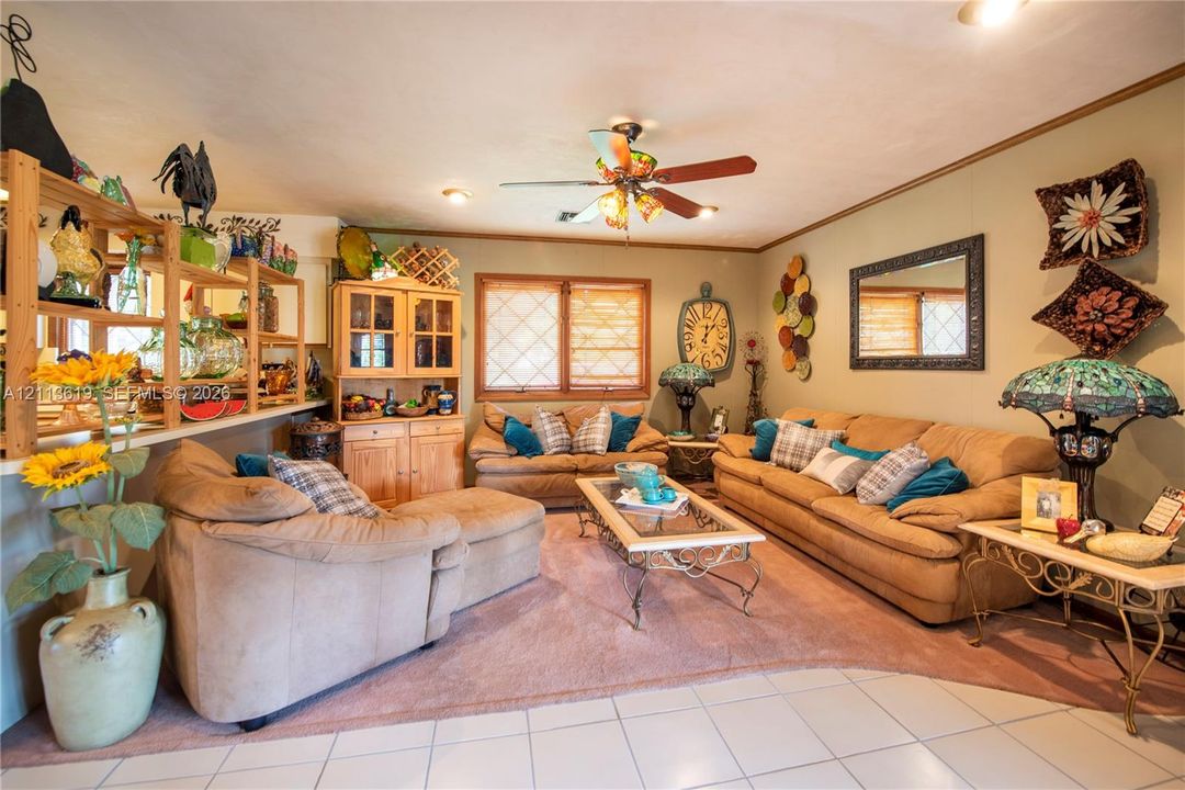 Living area featuring built-in cabinetry, ceramic tile flooring, neutral wall tones, diamond-grid window panes, and a ceiling fan with light fixture