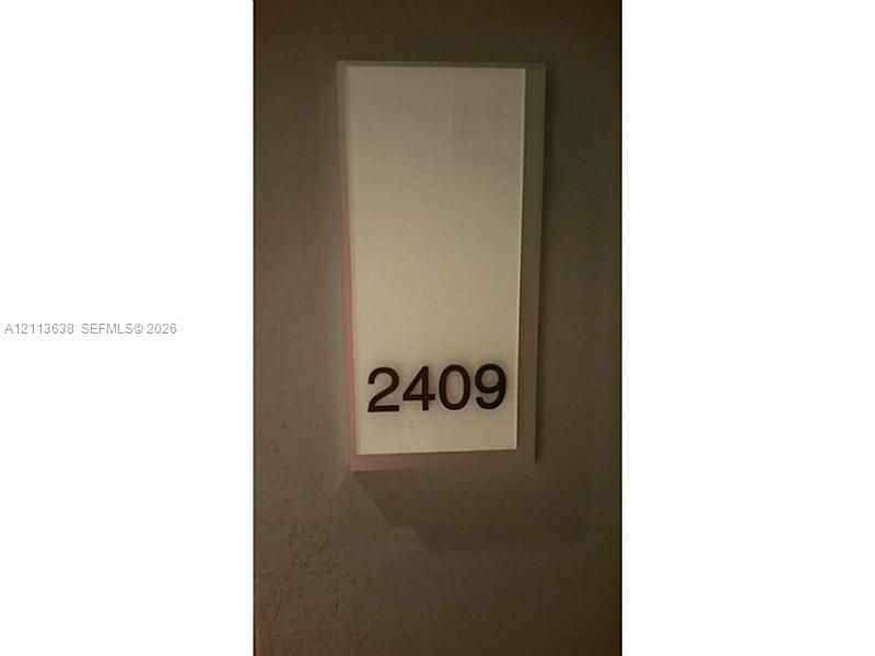 Wall-mounted unit identifier featuring a rectangular opaque panel with contrast lettering