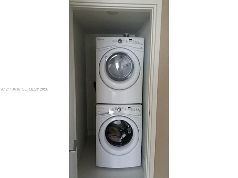 Stacked laundry unit featuring white front-loading machines housed within a recessed closet space