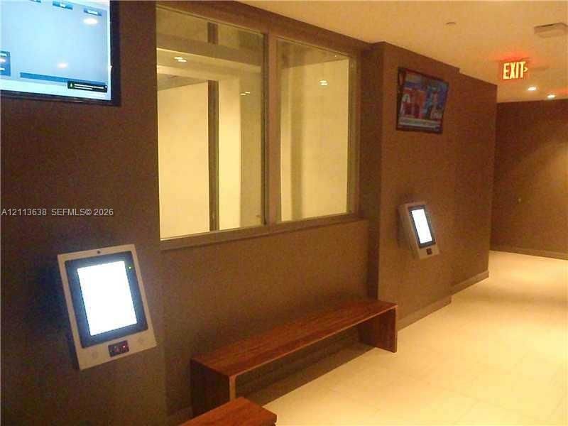 Wall-mounted digital kiosks, integrated wood-finish bench seating, recessed lighting, and expansive interior glass partition