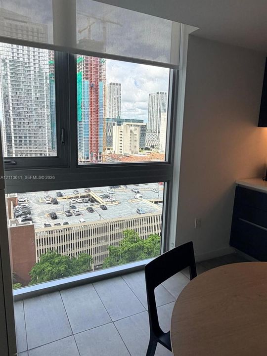 Floor-to-ceiling windows featuring dark-framed casement glass, a retractable solar shade, and large-format porcelain tile flooring