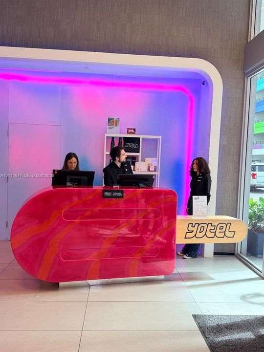 Custom-designed reception desk featuring a high-gloss finish, integrated accent lighting, and large-format floor tiling
