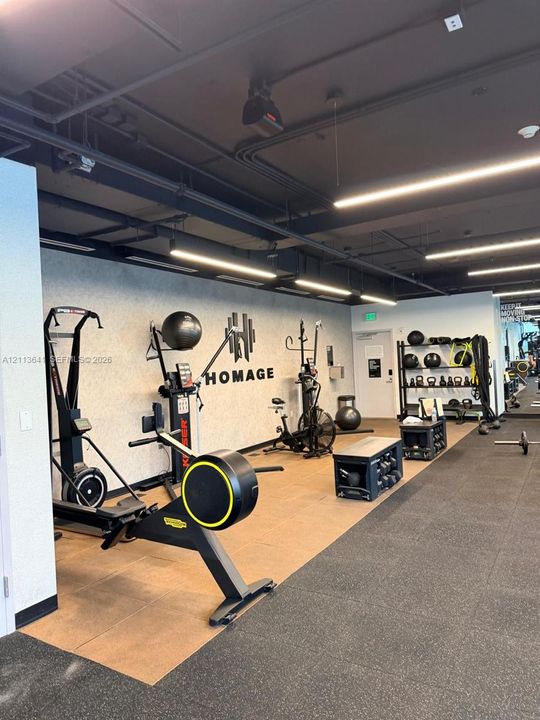Fitness space featuring exposed industrial-style ceiling, linear LED lighting, and rubberized flooring