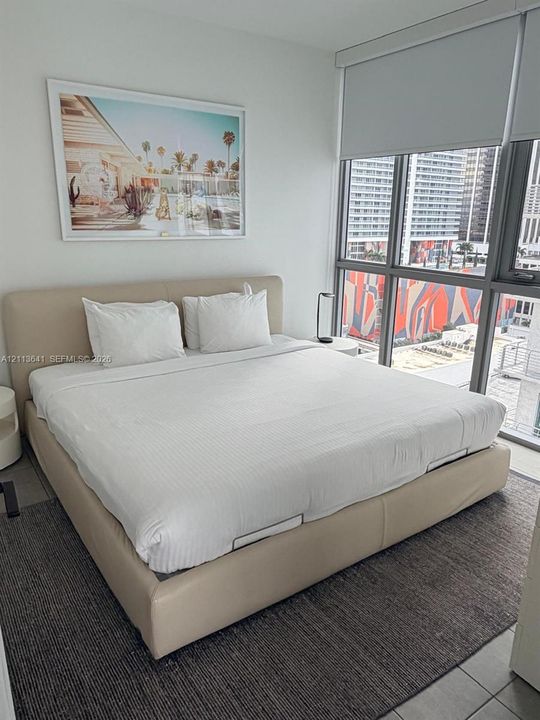 Floor-to-ceiling windows with roller shades, neutral-toned tile flooring, and clean-lined walls