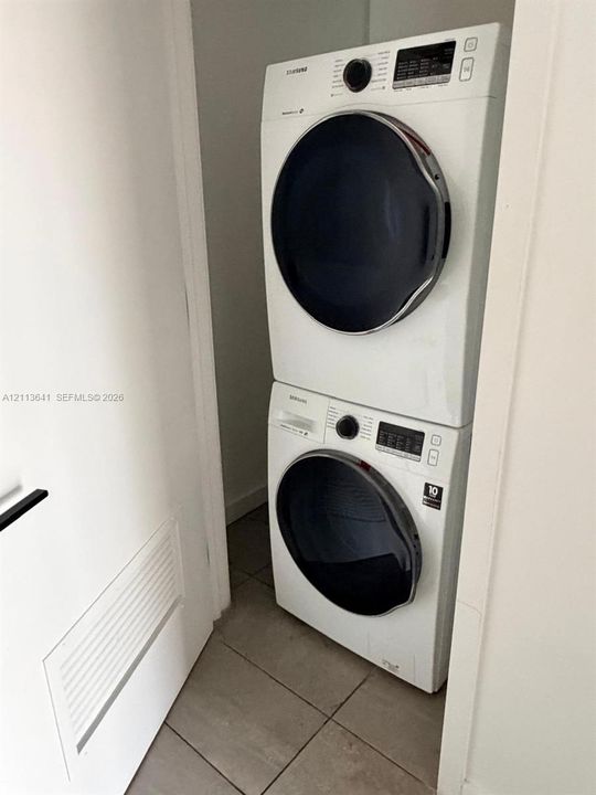 Stacked front-load washer and dryer unit with ceramic tile flooring