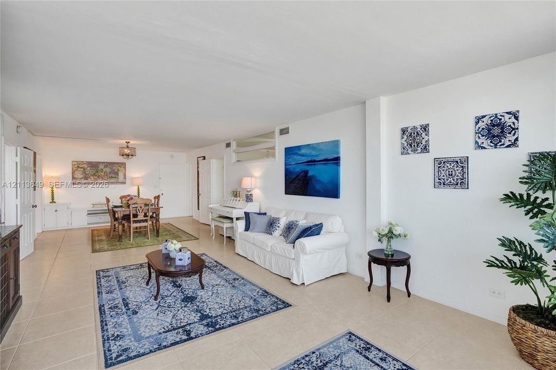 Open-concept interior featuring large-format neutral tile flooring, recessed lighting, and a multi-pane glass transom window