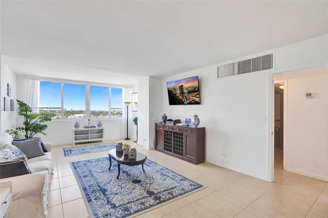 Living area featuring large-format ceramic tile flooring, expansive window wall, and white-painted walls
