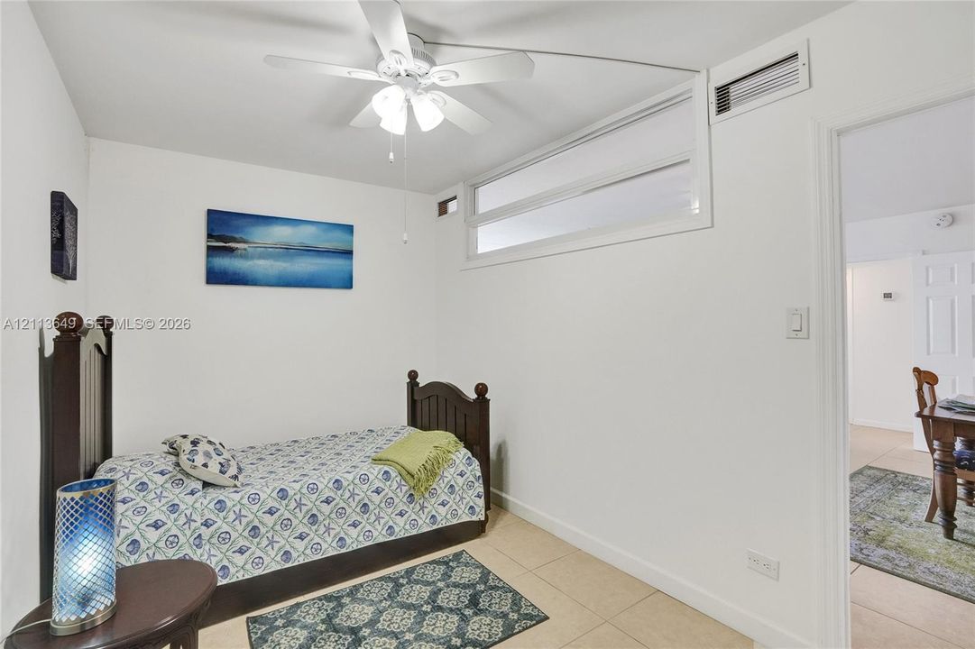 Room featuring ceramic tile flooring, a multi-light ceiling fan, and a high-set horizontal window