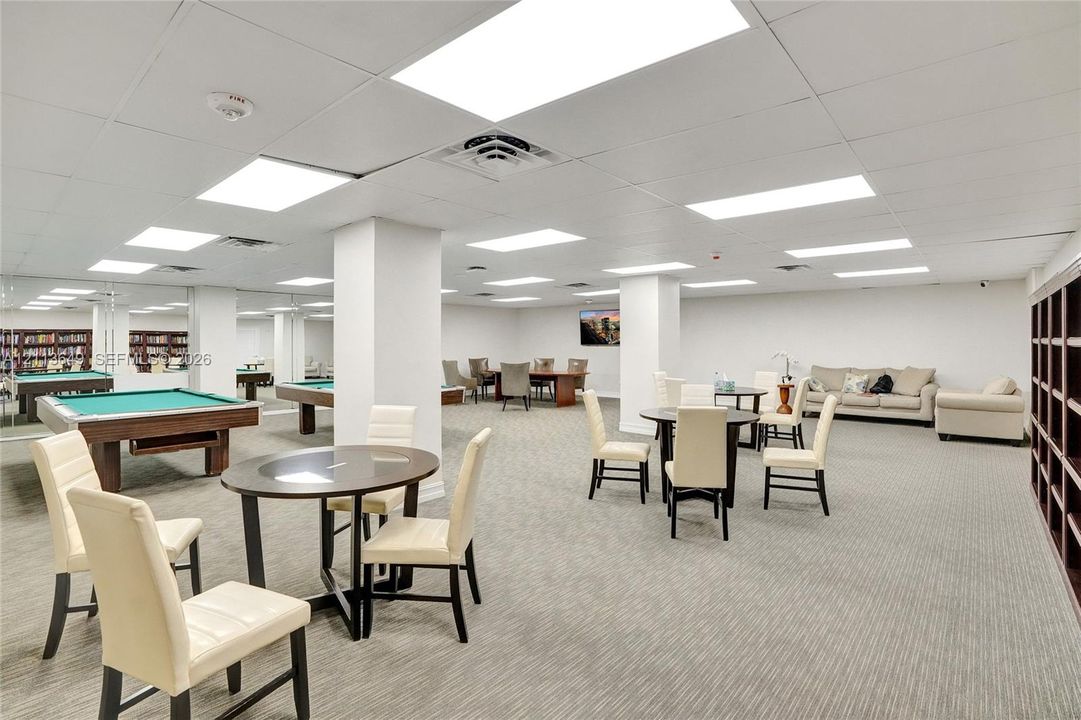 Open-concept room featuring wall-to-wall carpeting, recessed ceiling lighting, large mirrored wall panels, and built-in dark wood shelving