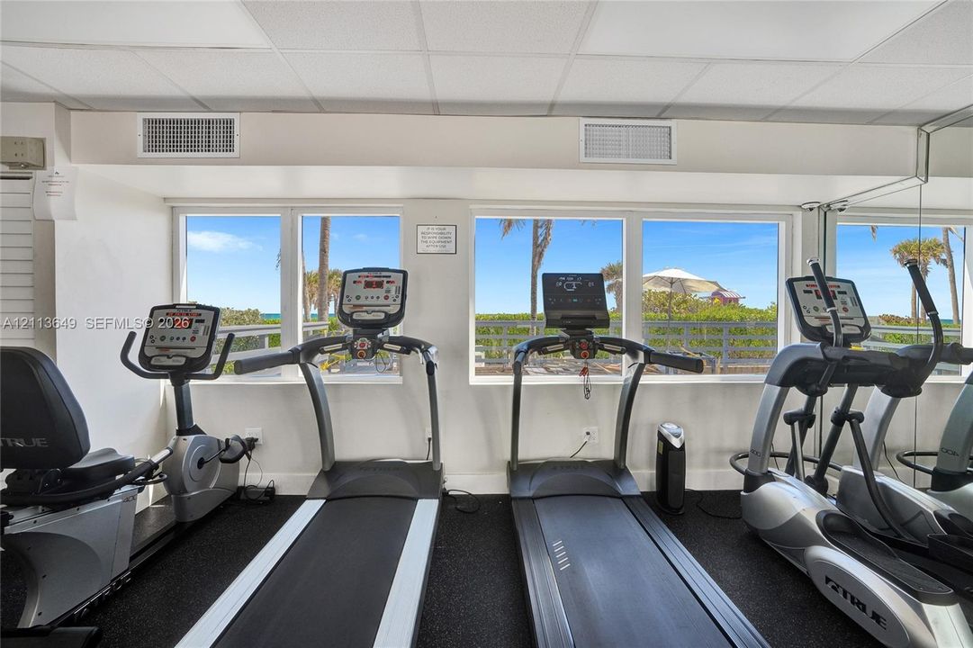 Fitness room featuring mirrored walls, rubberized flooring, and expansive windows with coastal scenery