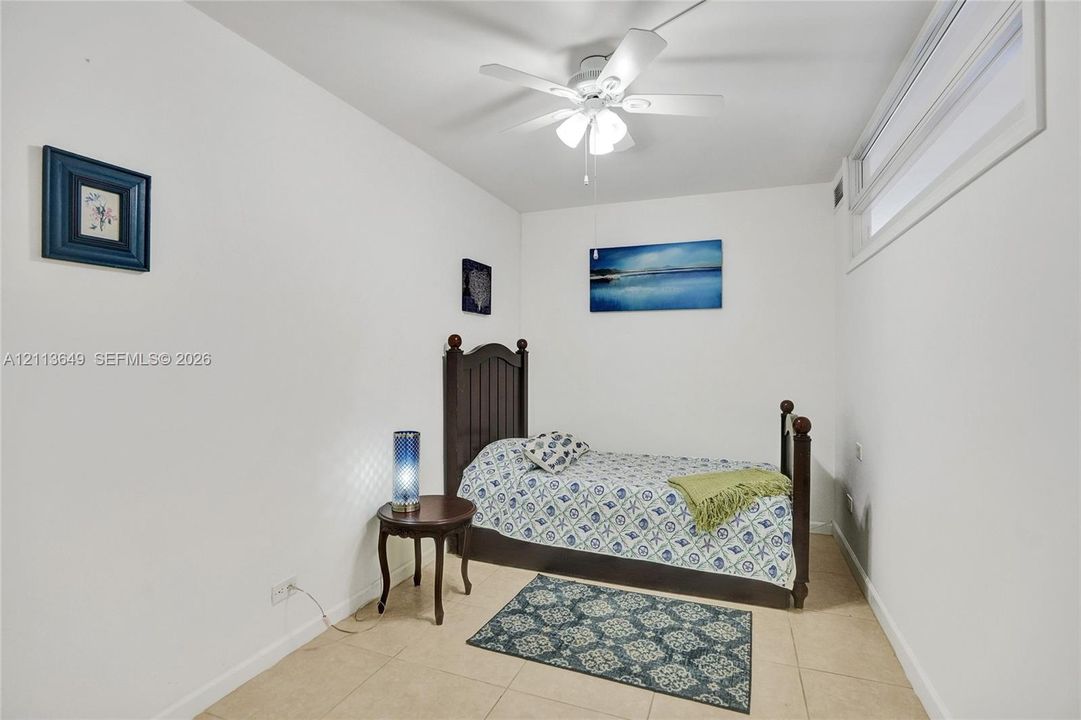Neutral interior featuring tile flooring, a high-mounted horizontal window, and a central ceiling fan with integrated light fixture