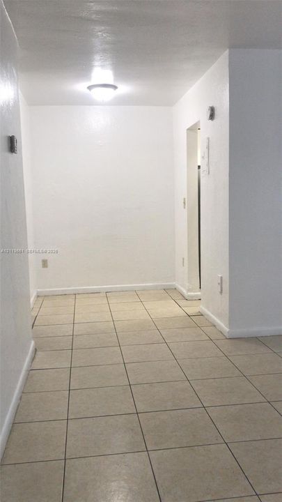 Neutral-toned ceramic tile flooring paired with crisp, white-painted walls, finished with a flush-mount ceiling light fixture