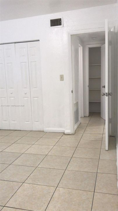 Neutral ceramic tile flooring, bi-fold closet doors, and walk-in storage area with integrated shelving