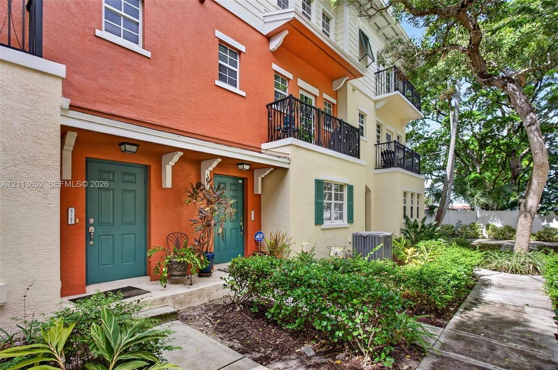 Multi-level facade featuring stucco exterior, private wrought-iron balconies, louvered shutters, and dual entrance doors