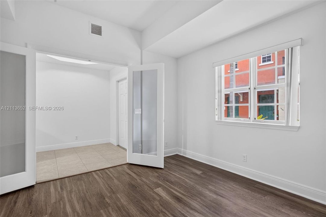 Room featuring wood-finish flooring, white walls, and a multi-lite window