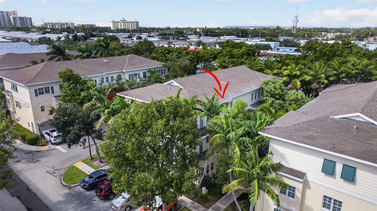 Aerial perspective of multi-story residence featuring light-toned siding, a pitched roof, and mature palm tree landscaping