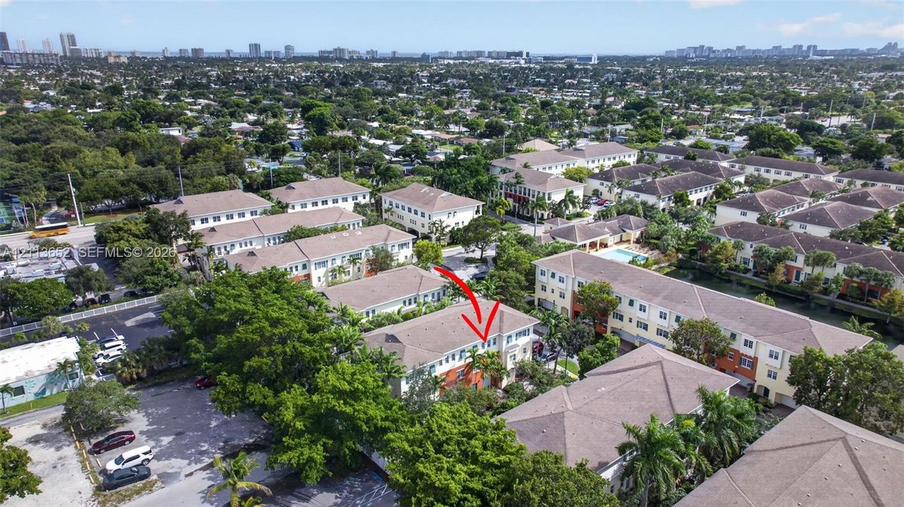 Aerial perspective of a multi-story residential building featuring a pitched roof, light-toned siding, and mature landscaping