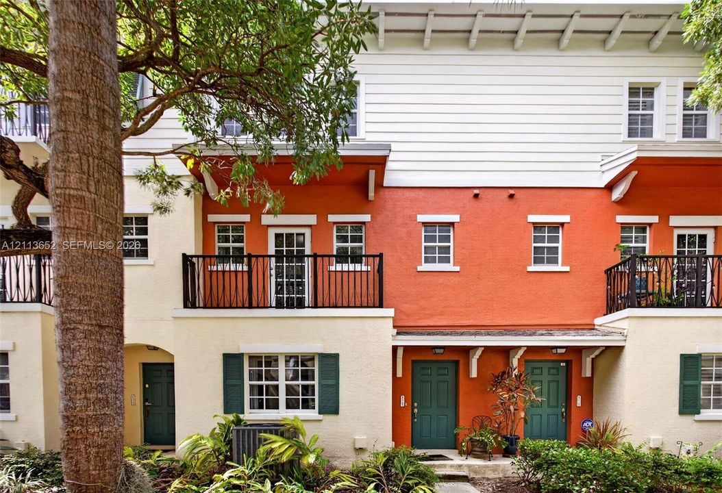 Multi-level exterior featuring stucco facade, horizontal lap siding, upper-level balconies with metal railings, and decorative wood corbels